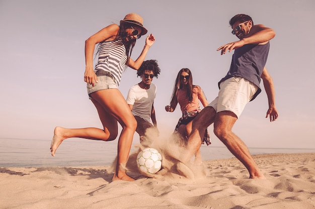 Photo fun time with friends. group of cheerful young people playing with soccer ball on the beach
