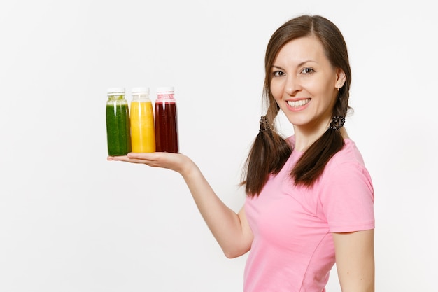 Fun woman holds row of green, red, yellow detox smoothies in bottles isolated on white background. Proper nutrition, vegetarian drink, healthy lifestyle, dieting concept. Copy space for advertisement.