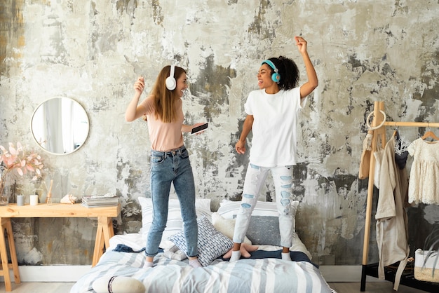 fun women dancing together on bed