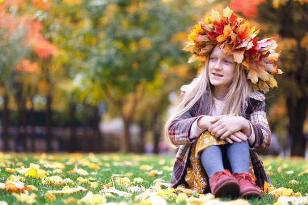 Fun young girl at the park with diadem from yellow maple leaves