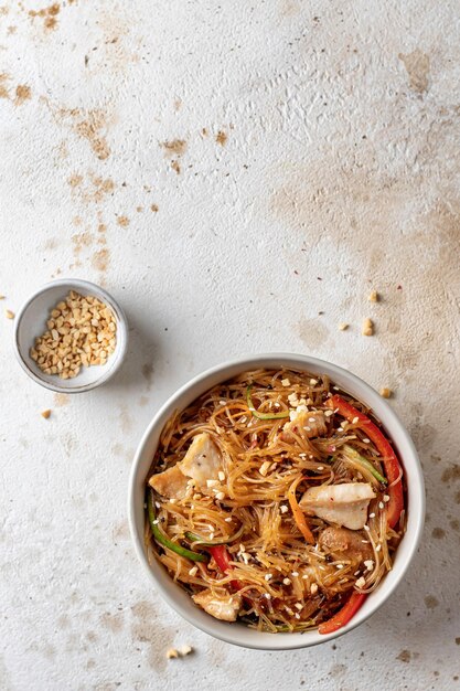 Photo funchose salad with chicken and vegetables in bowl on textured background top view with text space asian food menu