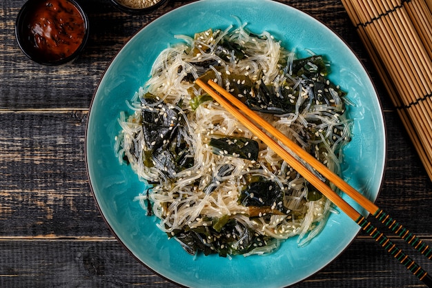 Funchoza salad with wakame on dark.