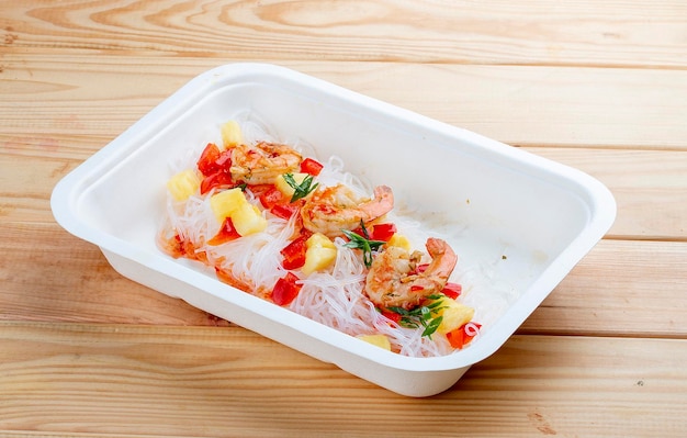 Funchoza with shrimp and pineapple with chili sauce Healthy food Takeaway food wooden background