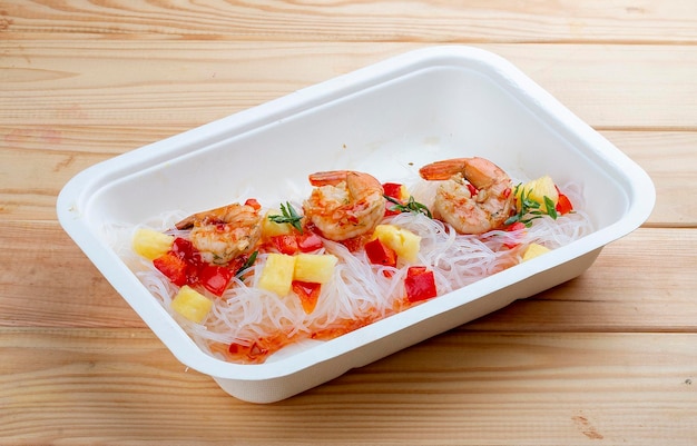 Funchoza with shrimp and pineapple with chili sauce Healthy food Takeaway food On a wooden background