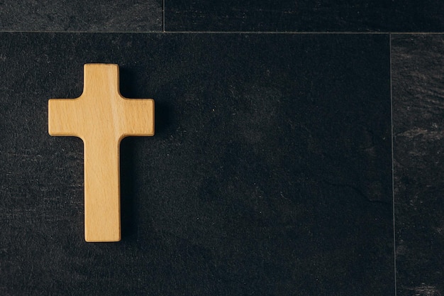 Funeral concept Wooden cross on black background top view copy space