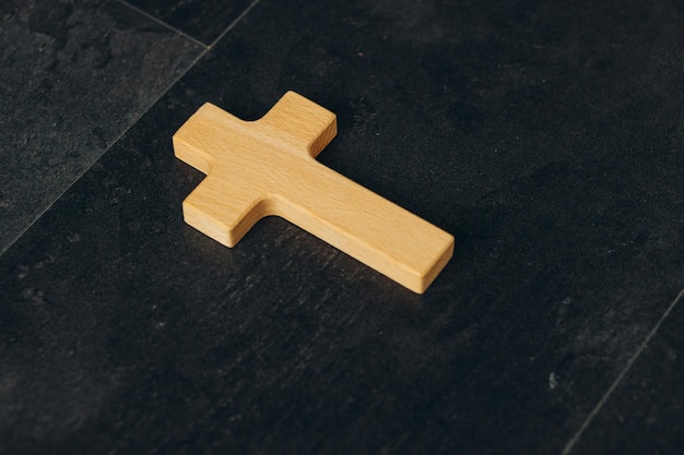 Funeral concept Wooden cross on black background top view copy space