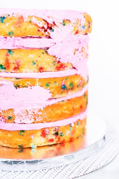 Foto strati di torta funfetti con glassa di crema al burro rosa.