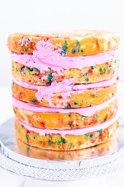Funfetti taartlagen met roze botercreme frosting.