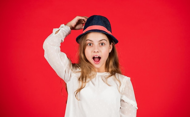 Funky beauty. small child long hair. beauty and style. Following her personal style. retro girl red background. happy little kid in retro hat. vintage fashion look. summer accessory collection.