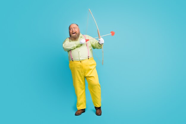 Funky overweight  man cupid shooting arrows into blue background empty space