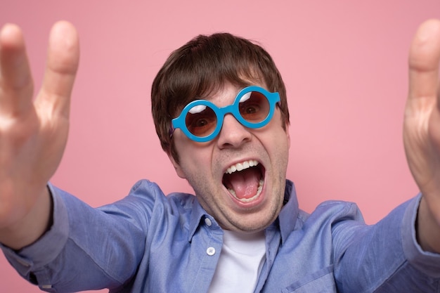 Selfie funky sul telefono il giovane uomo caucasico con gli occhiali estivi sta scattando un selfie