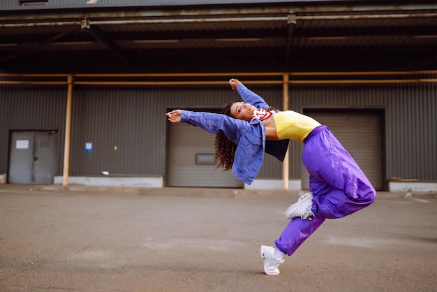 通りで一人で踊るアメリカのバンダナを持つファンキーな若い女性スポーツダンスと都市文化