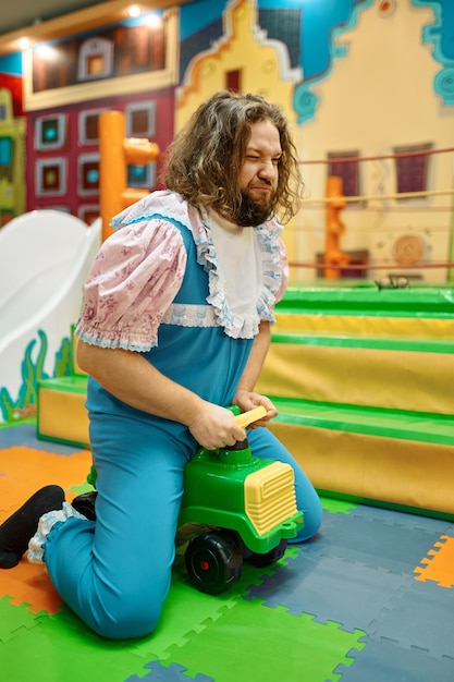 Funny adult man and woman like babies driving toy car