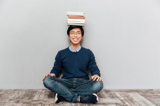 Funny asian student sitting on the floor. smiling. looking at the camera