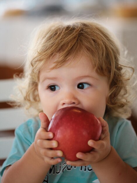 Photo funny baby eat apple kid eating fruit little boy biting apple healthy nutrition for kids solid food