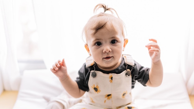 Funny baby girl sitting near window