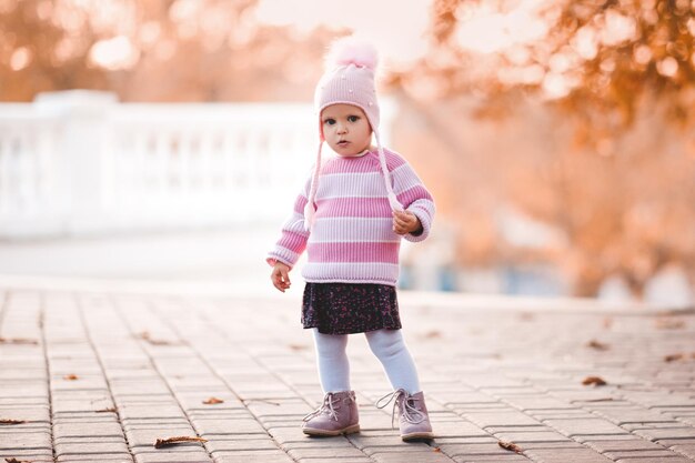 Funny baby girl standing in park over autumn nature background