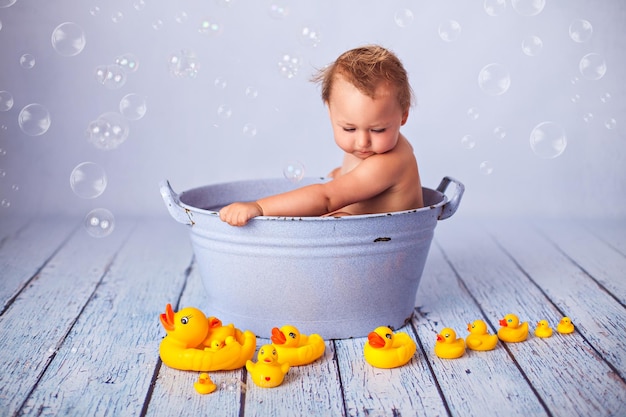 写真 カラフルなおもちゃのアヒルと浴槽でお風呂に入る面白い女の赤ちゃん