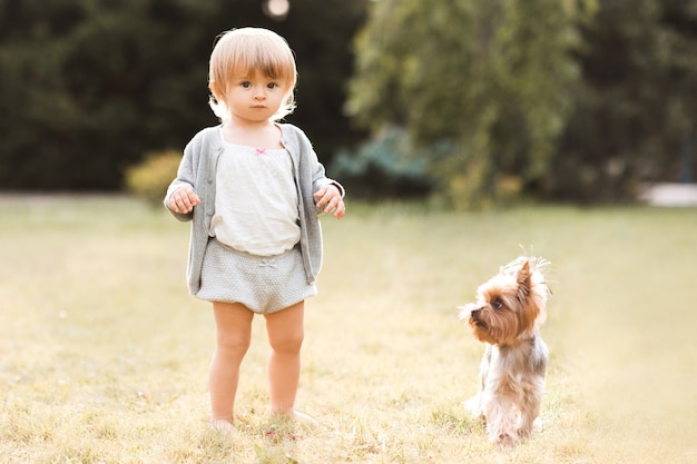 Funny baby girl walking with yorkshire terrier puppy