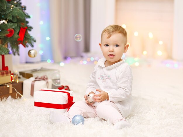 Bambina divertente con il giocattolo di natale vicino all'albero di natale