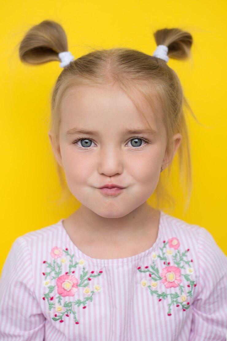 funny baby girl, on yellow background, funny face