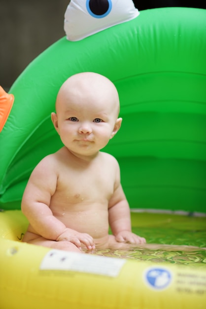 Funny baby in inflatable pool on the yard