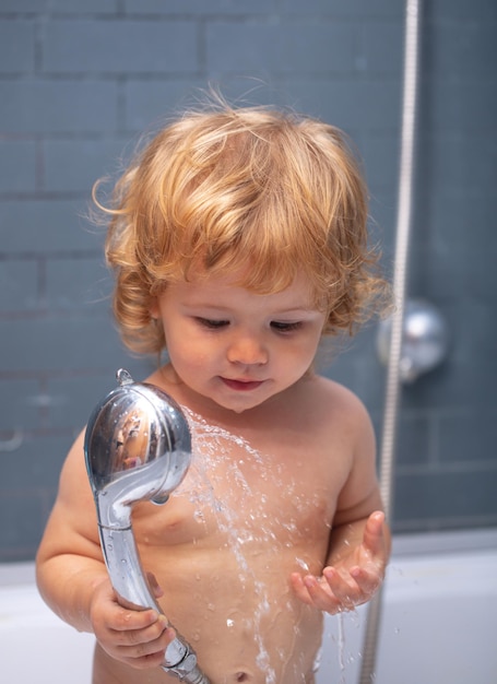 Photo funny baby kid bathed in foam and washing in bathtub at home