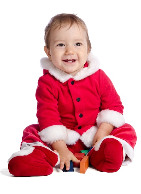 Funny baby in Santa Claus clothes on white background with cubes
