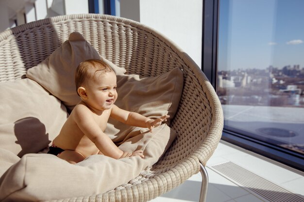 Funny baby sitting on chair near window