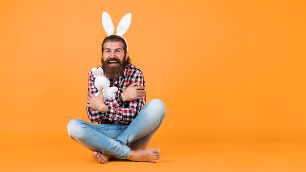 Foto divertente uomo barbuto indossare orecchie da coniglio ragazzo in costume da coniglio divertirsi festa di primavera celebrazione caccia all'uovo uomo felice brutale su sfondo giallo coniglietto divertente buona pasqua spazio copia