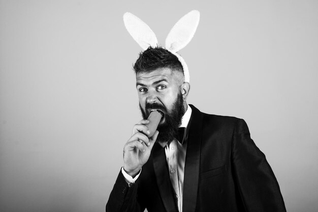 Funny bearded man with carrot and rabbit ears on isolated background Rabbit cosplay Bearded hipster in suit with ears and carrot