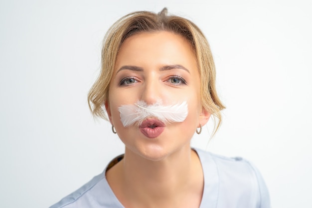 Funny beautician with a white featherlike mustache poses on white background depilation concept