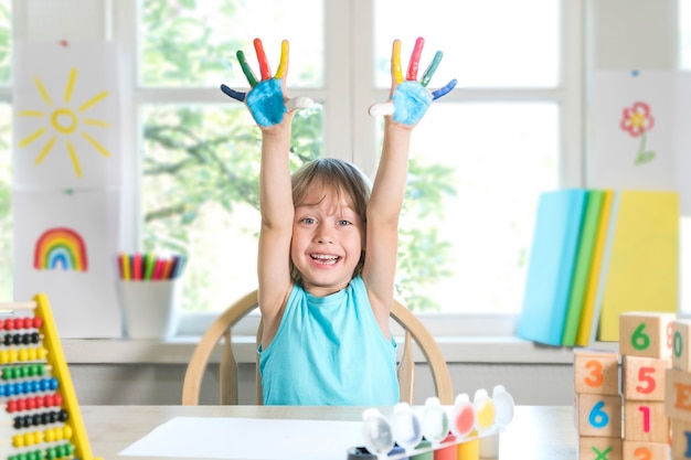 Funny beautiful happy child boy shows hands dirty with paint kid draws laughing with paint