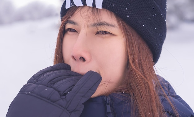 사진 겨울 패션 의류를 입은 재미있는 미인 여자가 눈 스키 리조트에서 손을 물고 있는 재미있는 얼굴을 만들고 있다