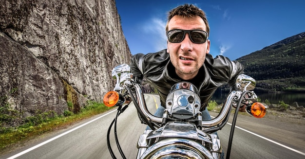 Funny Biker in sunglasses and leather jacket racing on mountain serpentine. Filter applied in post-production.