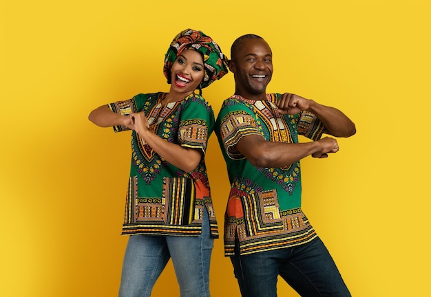 Funny black man and woman in african costumes dancing together