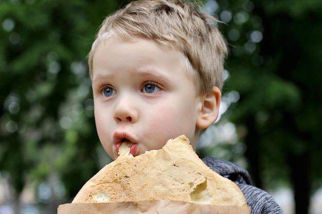 Funny blondheared toddler eating Georgian bread with appetite