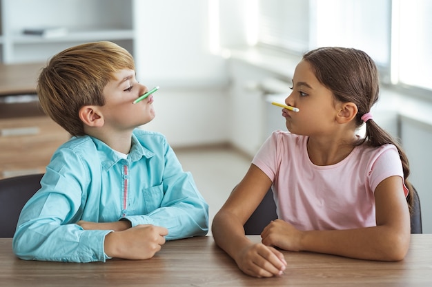 おかしな男の子と女の子が机で遊んでいます