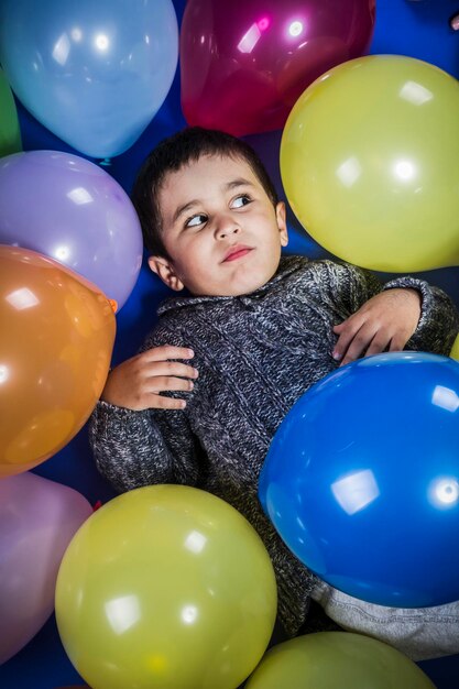 Funny boy playing with balloons of many colors