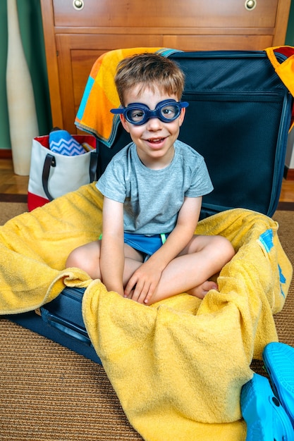 Photo funny boy smiling sitting inside a suitcase ready to go on vacation