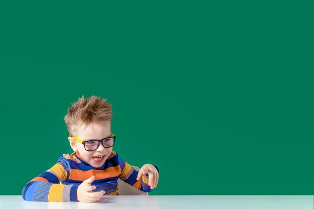 Funny boy with glasses at the table playful mood Copy space