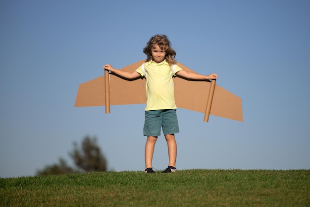 장난감 판지 비행기 날개를 가진 재미있는 소년 비행 시작 자유 개념 어린이 비행사 의상을 입고 비행