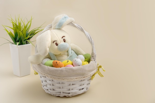 Funny bunny in an easter basket among eggs on a beige\
background easter content