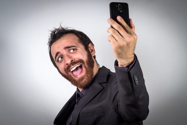 Funny businessman is using his smartphone to take a selfie