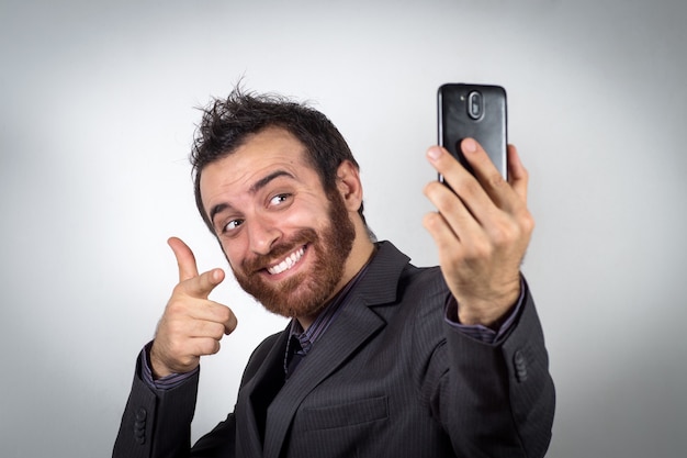Забавный бизнесмен использует свой смартфон, чтобы сделать селфи