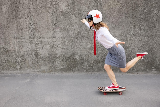 Funny businesswoman riding skateboard outdoor