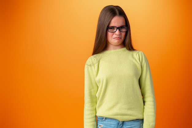 Funny caucasian teen girl in eyeglasses isolated on orange background