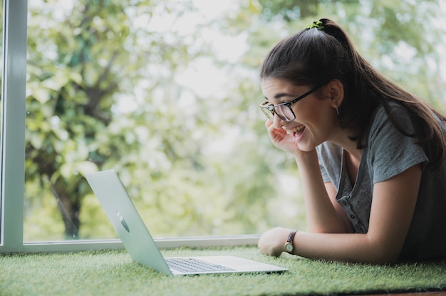 Photo funny and cheerful girl watching comedy movie on laptop with spectacles and pet dog while relaxing at home sitting on couch