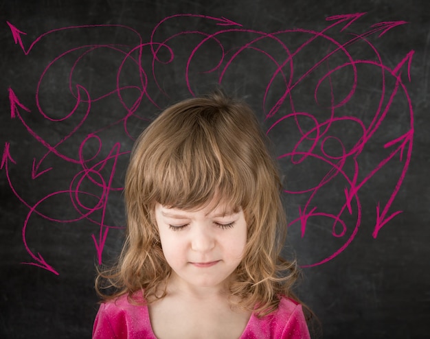 Funny child against blackboard. Smiling kid in class. Drawing arrows. Conception