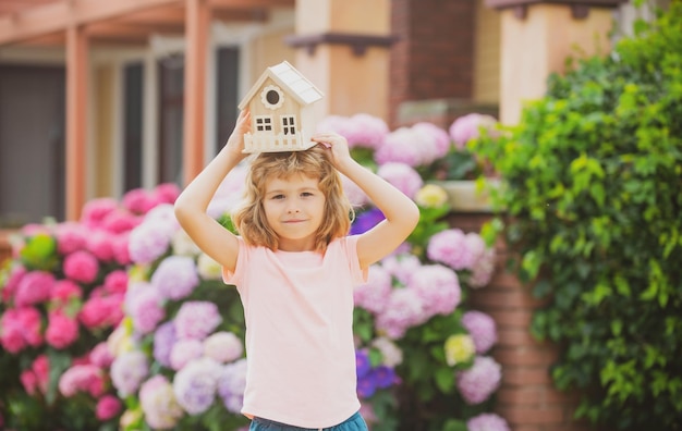 Funny child boy dreaming about a new house or home.